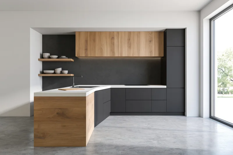 Modern minimalist kitchen with dark matte cabinets and wooden accents featuring a white countertop and open shelving near a large window