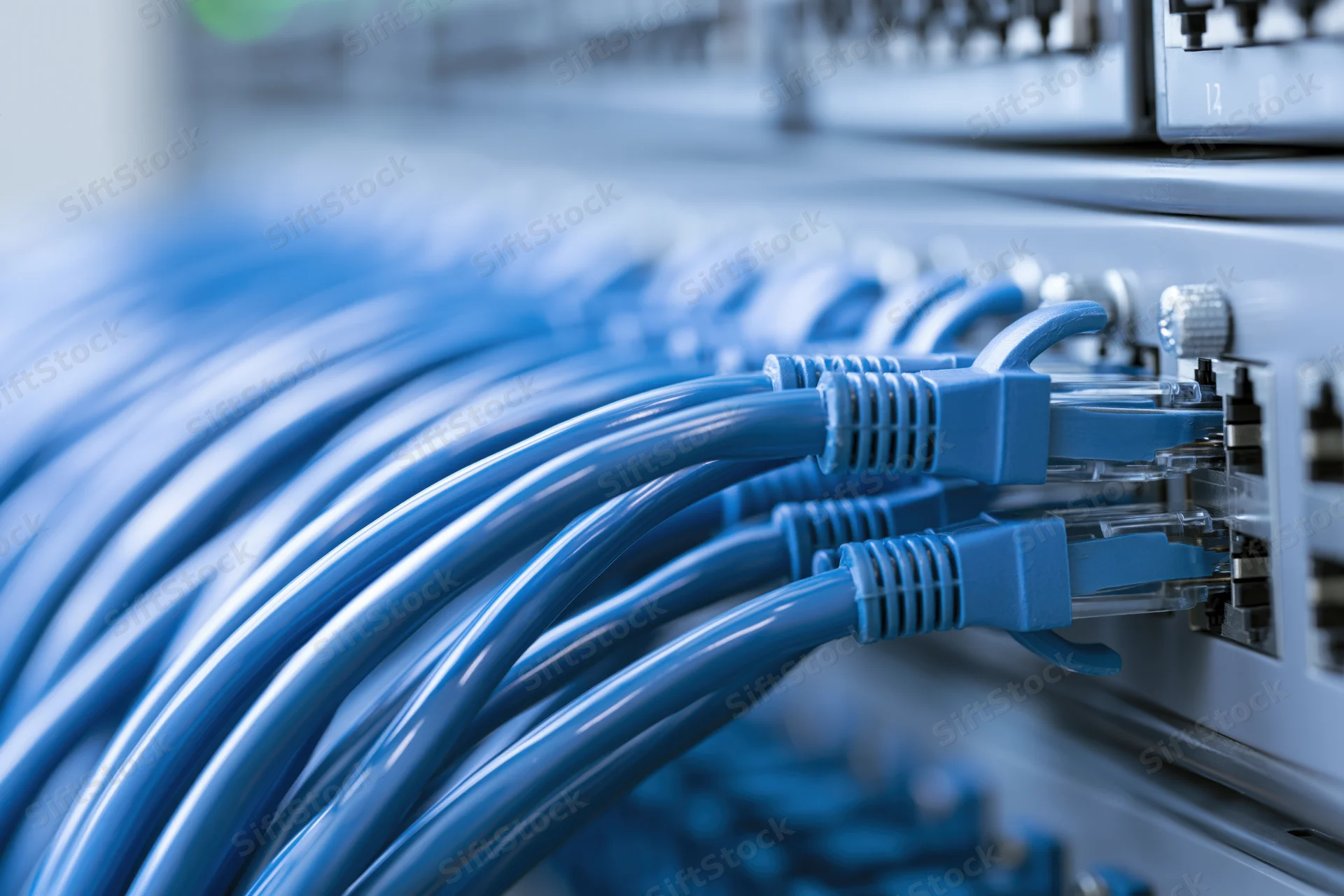 Blue ethernet cables plugged into a network switch in a server rack