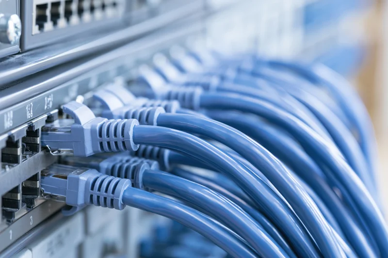 Blue ethernet cables plugged into a network switch in a server rack