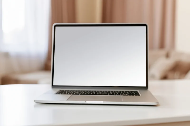 Open laptop with blank white screen on white desk in home office setting