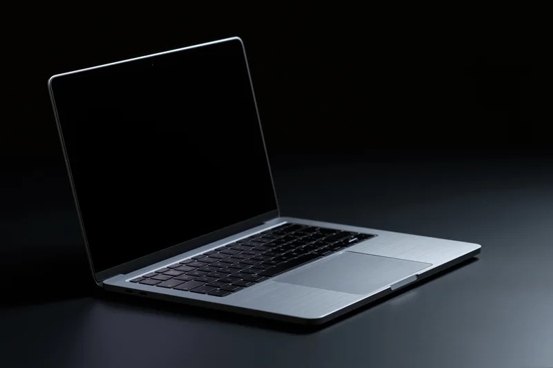 Open silver aluminum laptop with dark blank screen on dark surface