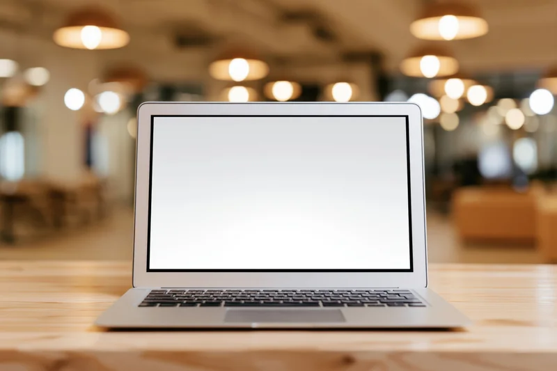 Silver laptop with blank white screen on wooden desk in office setting