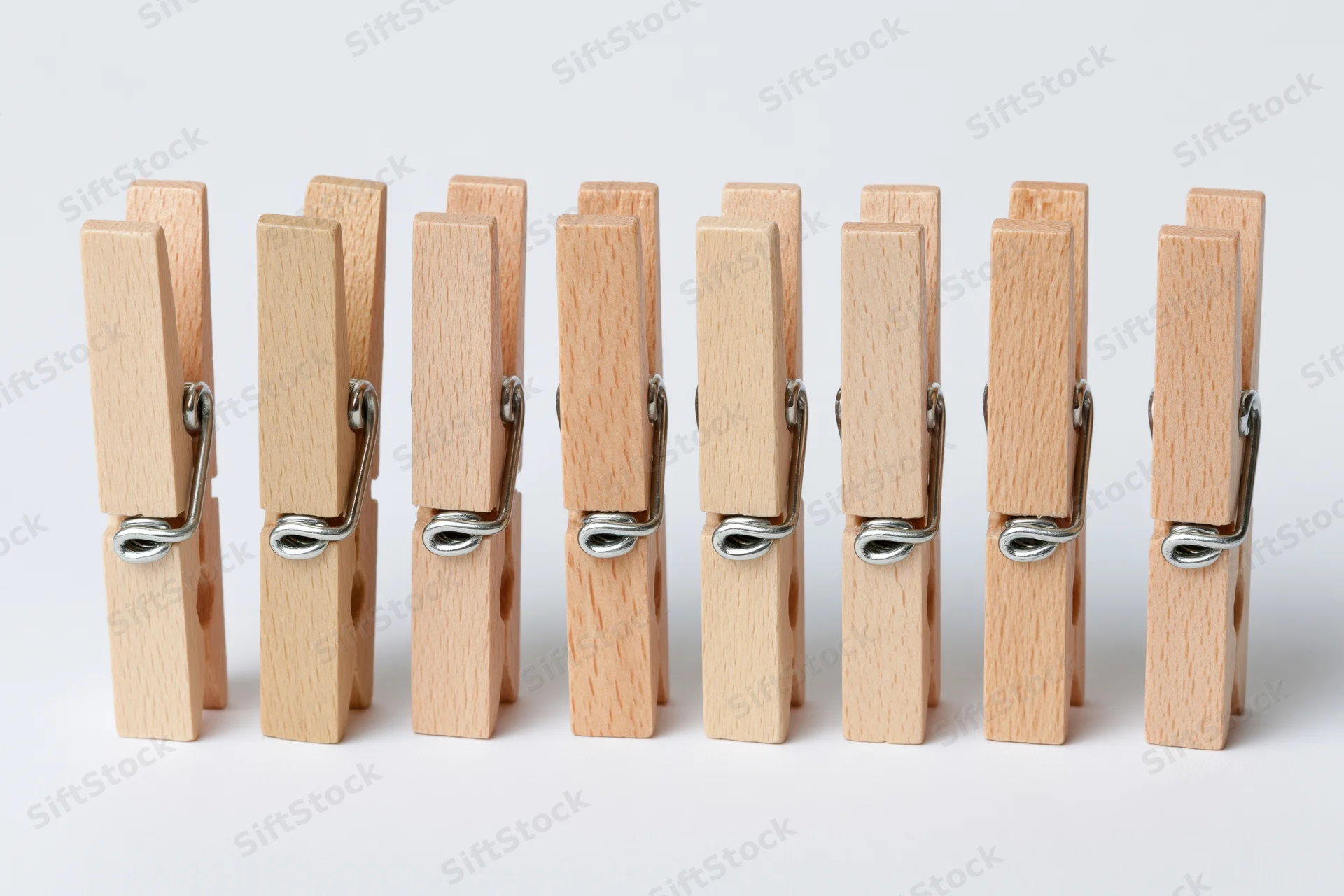 Six wooden clothespins standing upright in a row on a white background