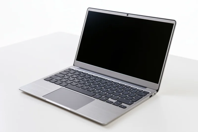Open silver aluminum laptop with blank black screen on white surface