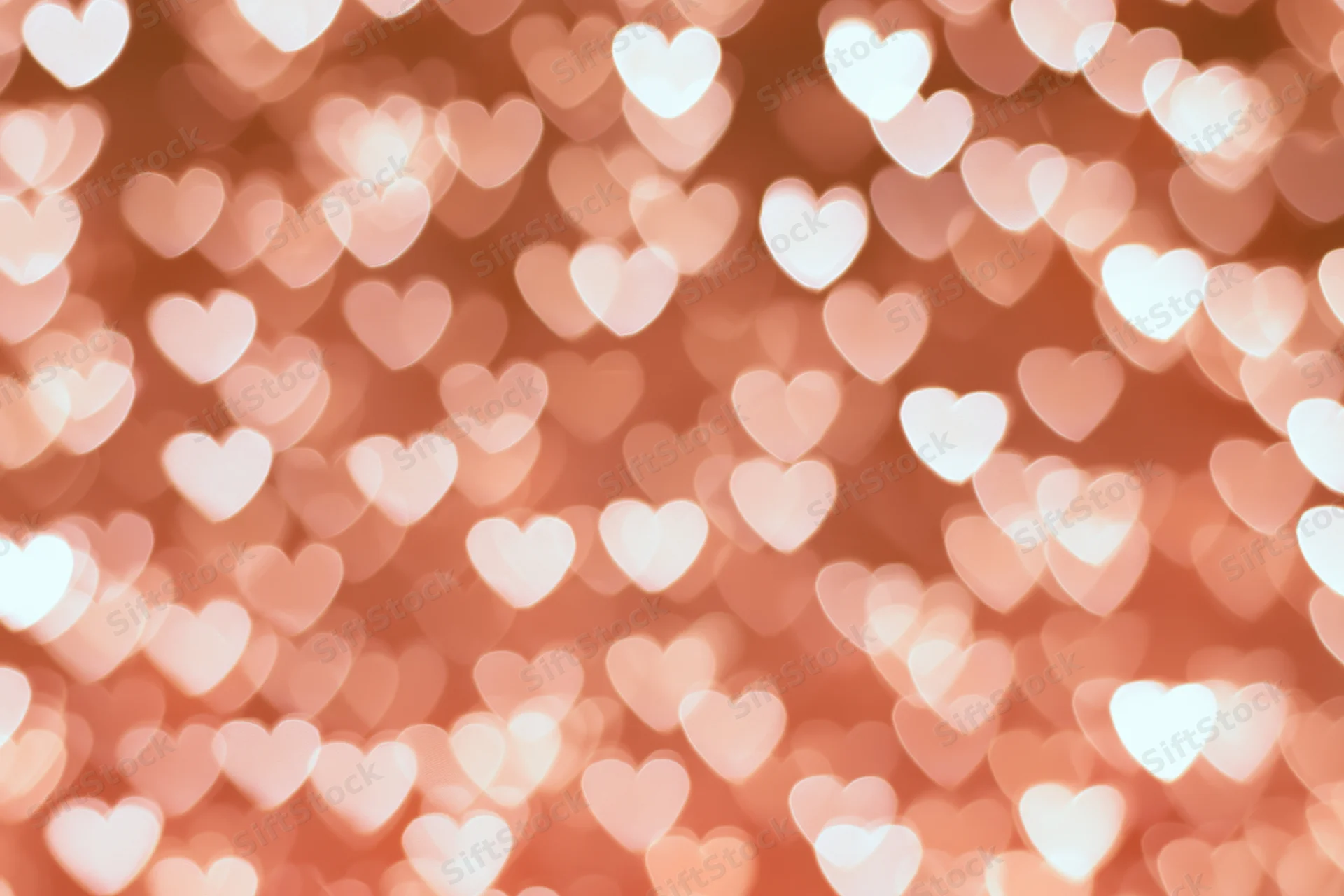 Soft bokeh background of out-of-focus heart-shaped lights in warm pink tones