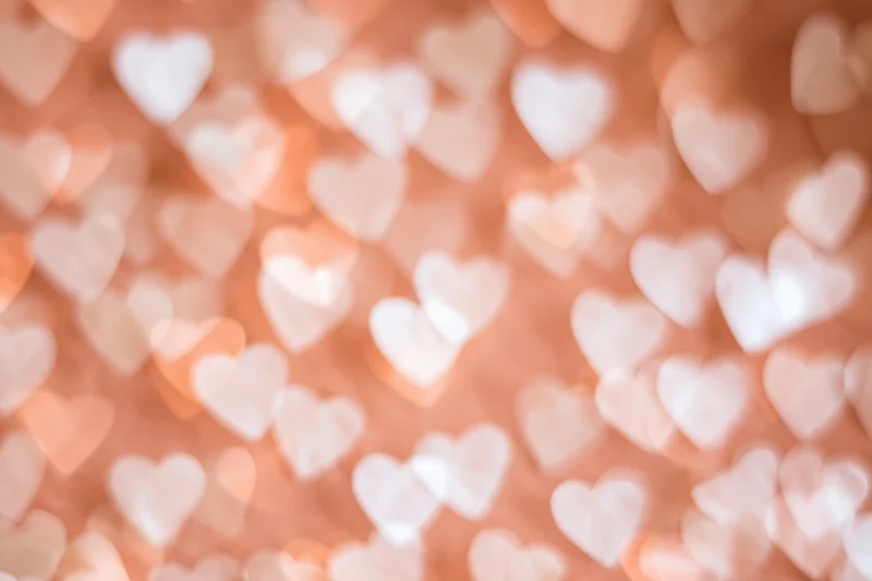 Soft bokeh background of out-of-focus hearts in warm pink tones