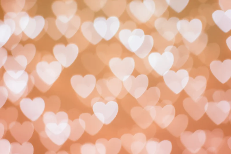 Soft bokeh background with out-of-focus heart shapes in warm peach and pink tones