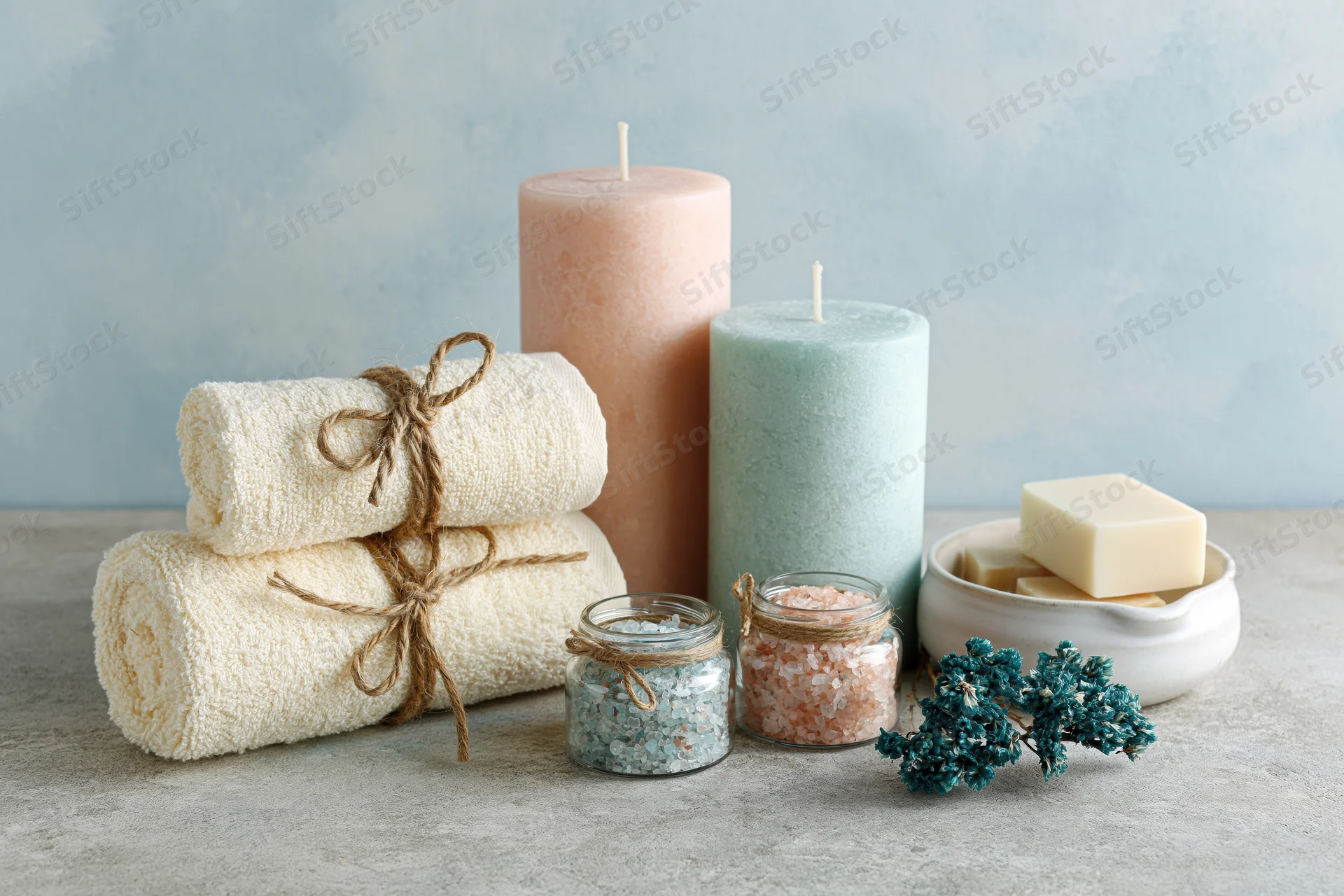 Spa wellness flat lay with candles, towels, bath salts and soap on concrete surface