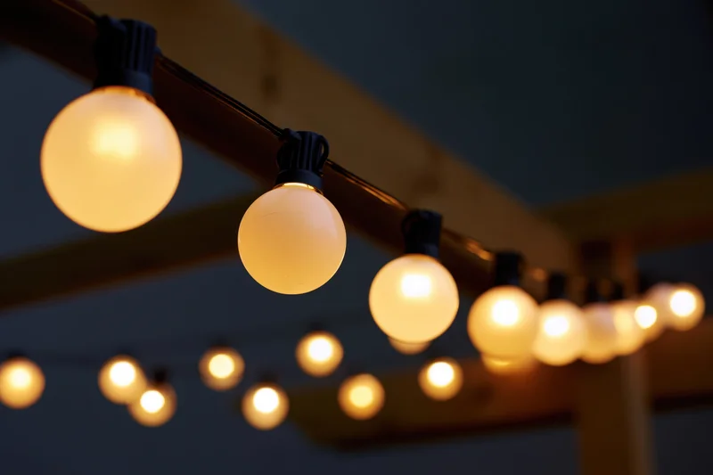 String of round globe edison bulbs hanging outdoors at night under wooden beams