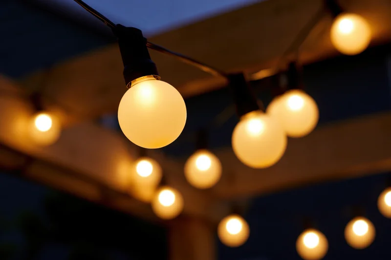String of round globe edison bulbs hanging outdoors at night under wooden beams