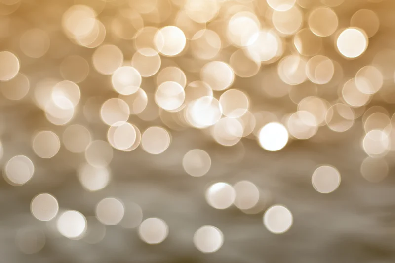 Blurred golden lights reflecting on calm water surface in soft focus