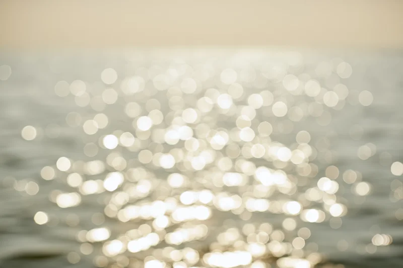 Sunlight reflecting off calm water surface in soft bokeh effect