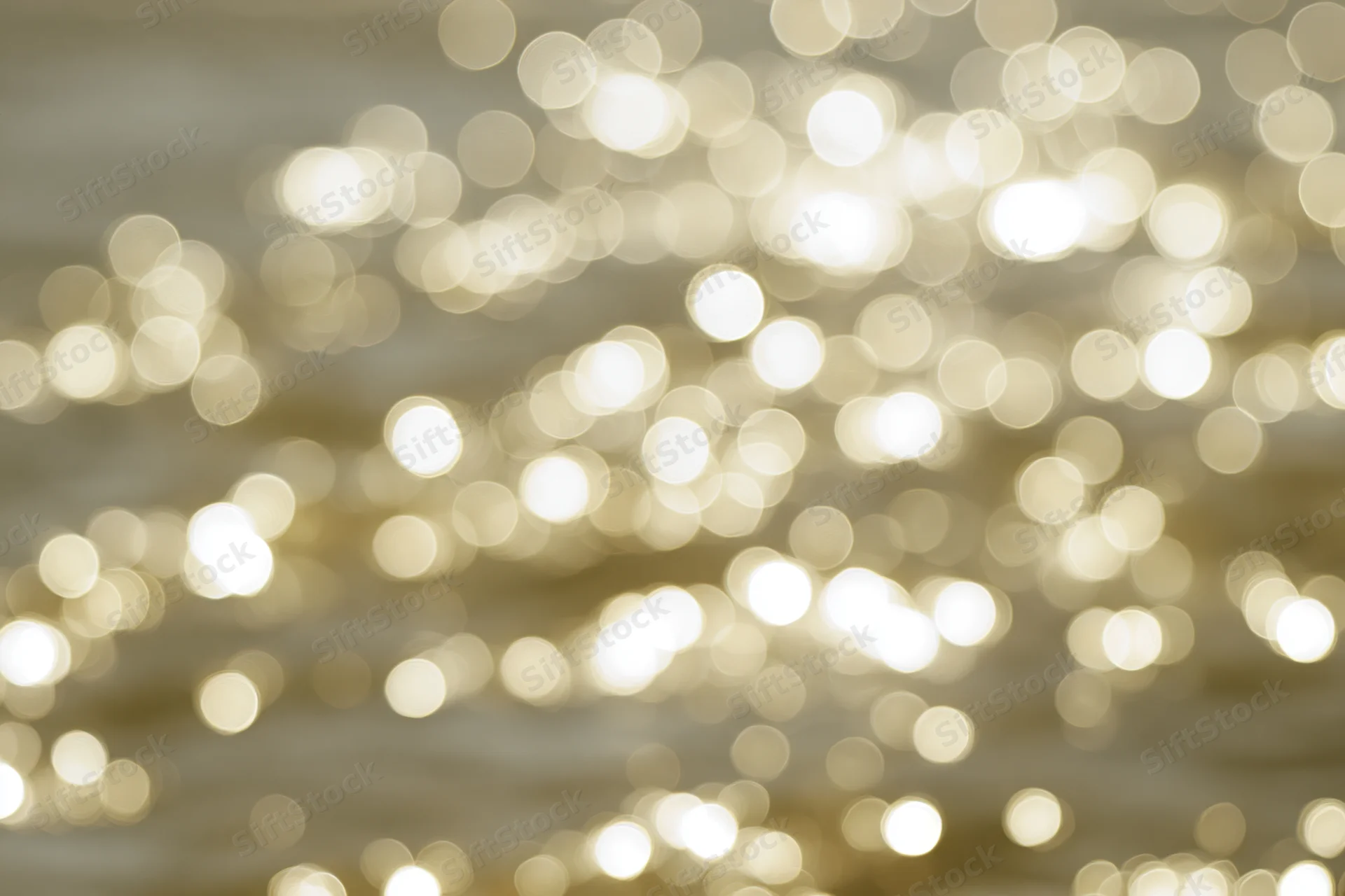 Blurred golden lights reflecting on calm water surface in closeup