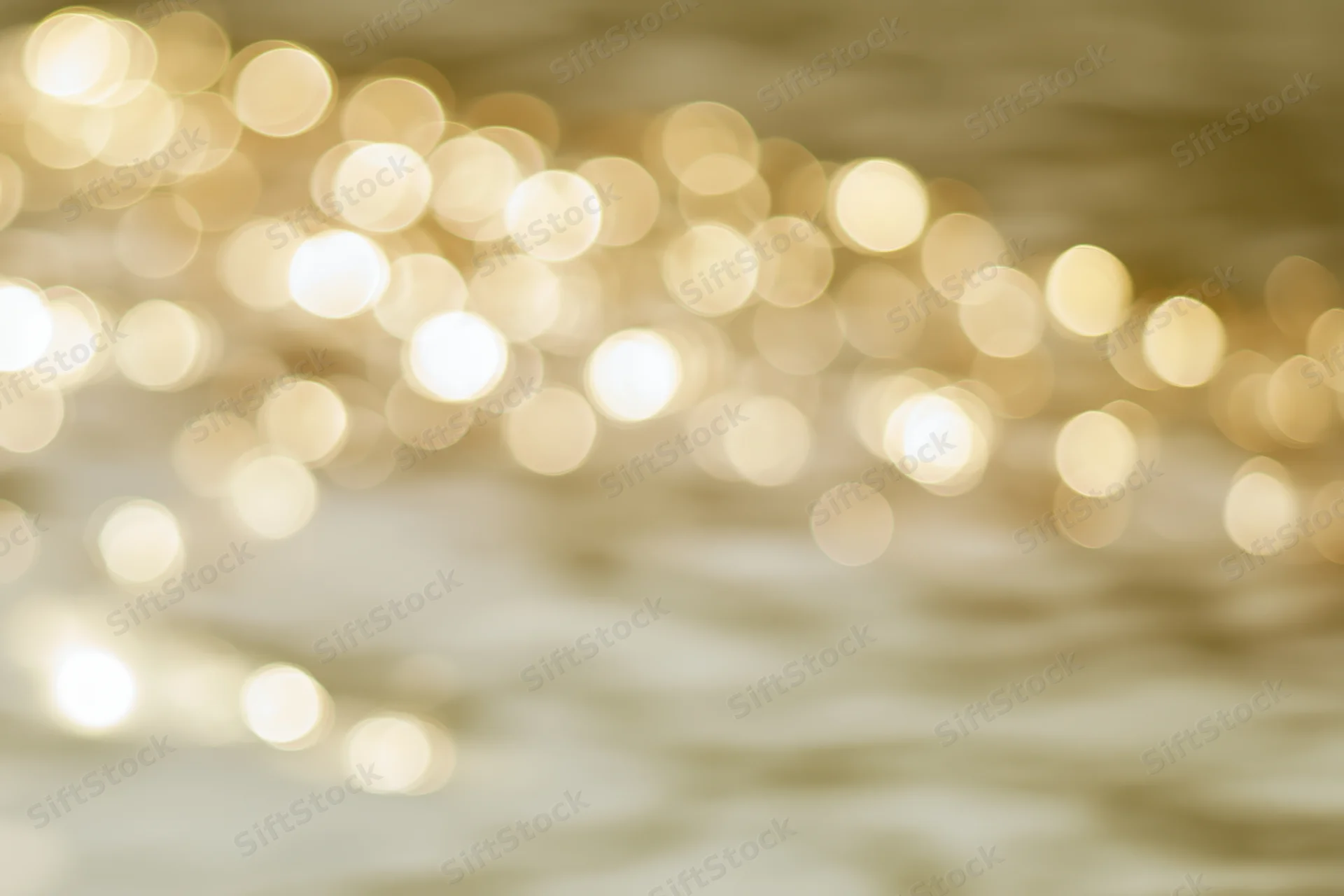 Sunlight reflecting off calm water surface in soft golden bokeh