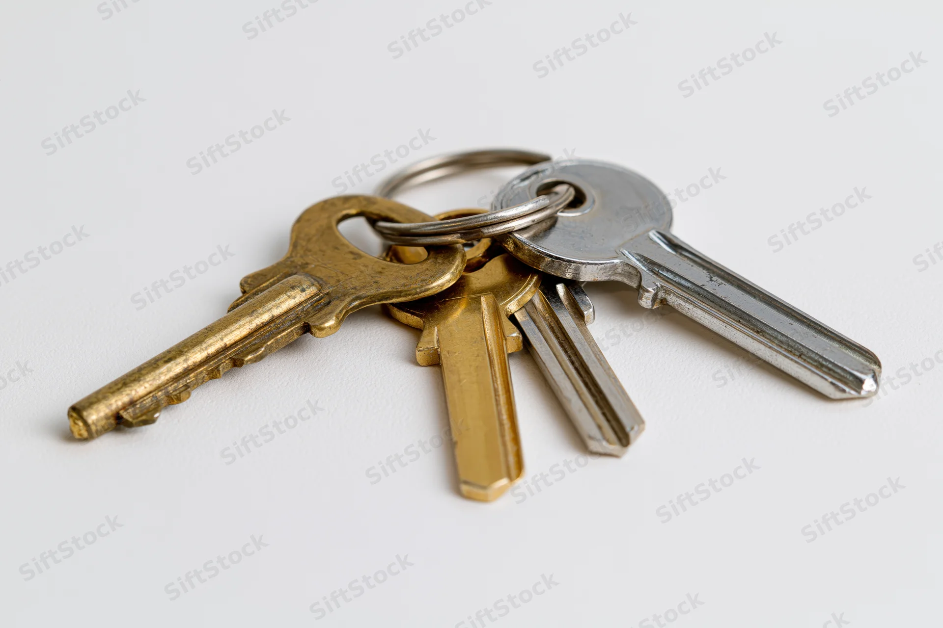 Three metal keys on a small ring lying flat on a plain white surface