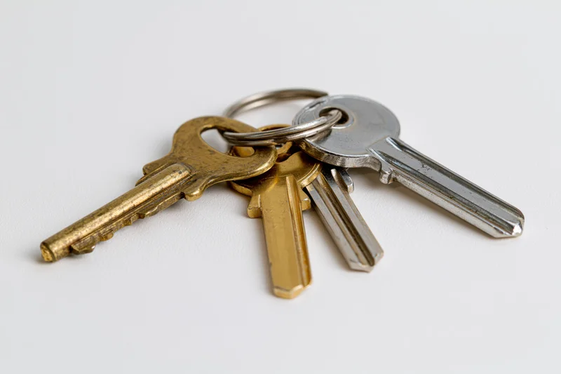 Three metal keys on a small ring lying flat on a plain white surface