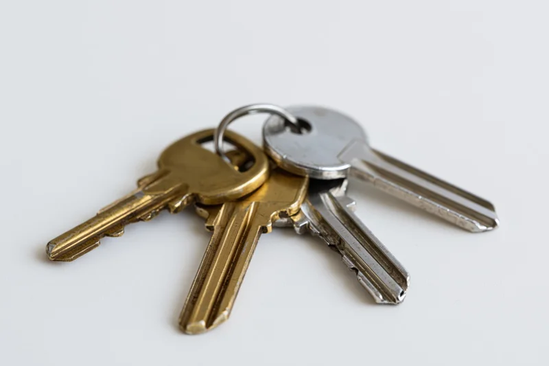 Three metal keys on a small ring lying flat on a plain white surface