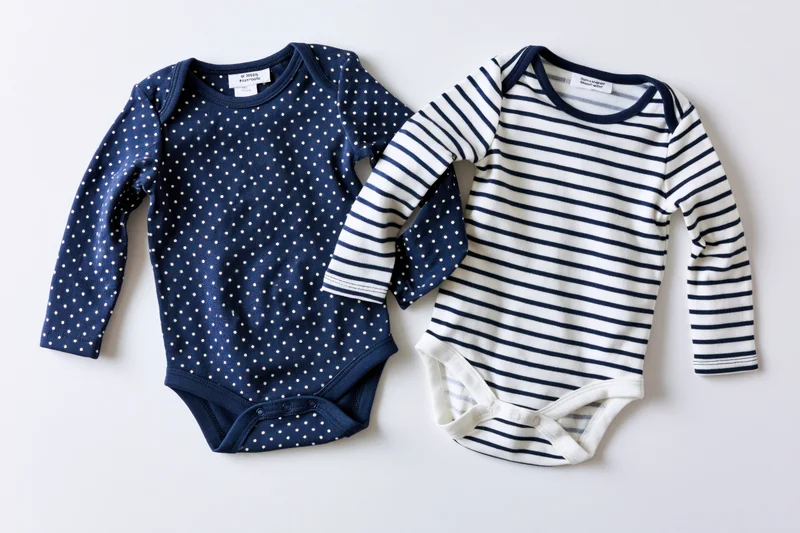 Two infant longsleeve bodysuits laid flat on white background