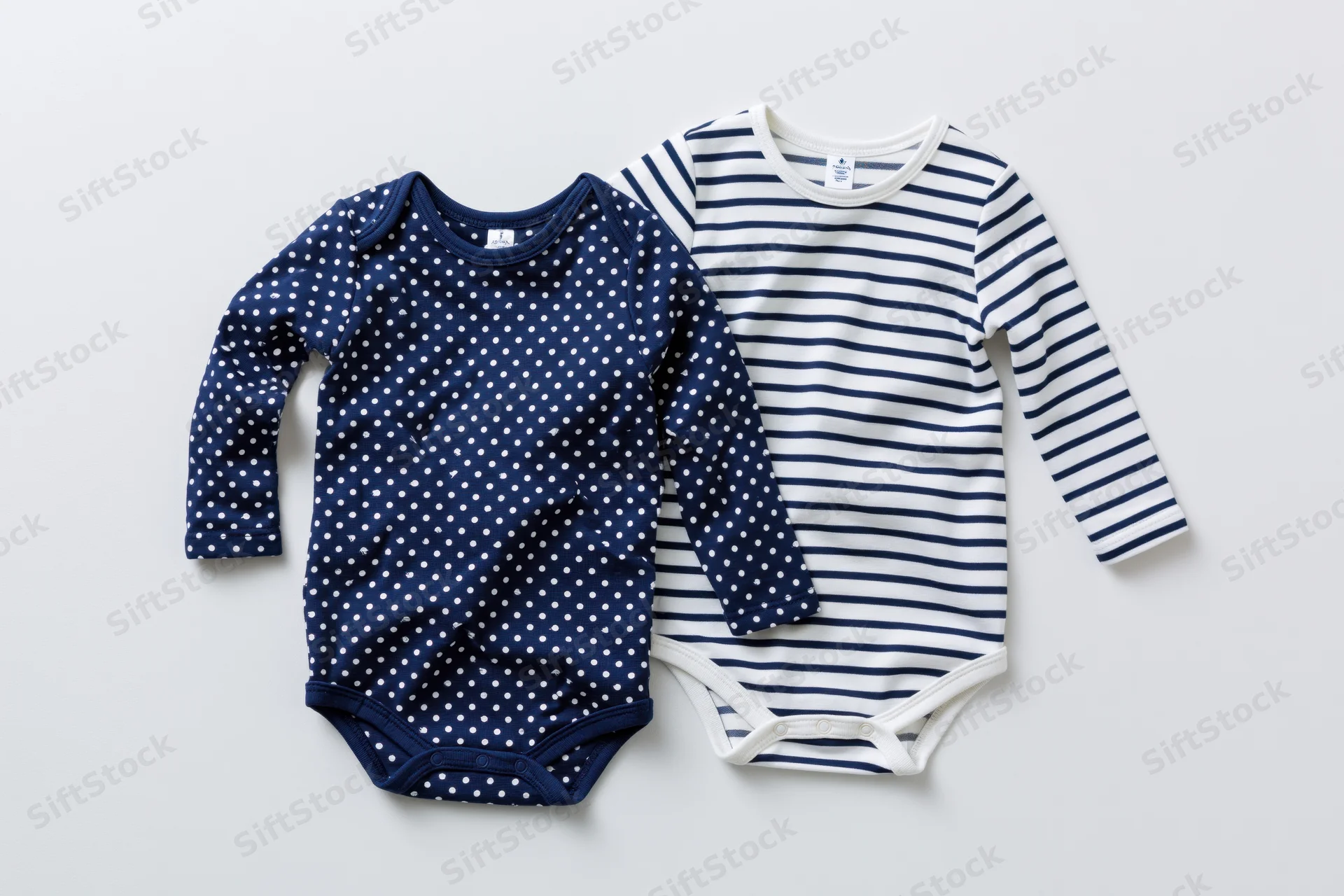 Two infant longsleeve bodysuits laid flat on white background