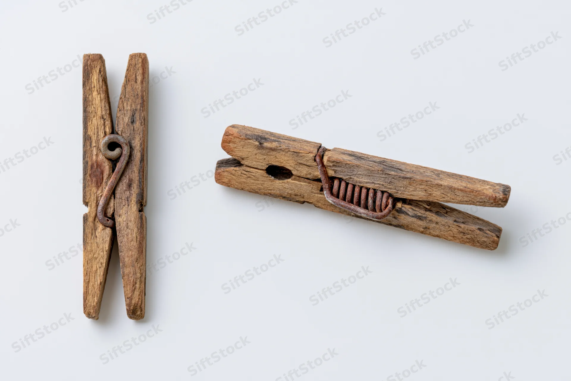 Two views of an aged wooden clothespin with metal spring on white background