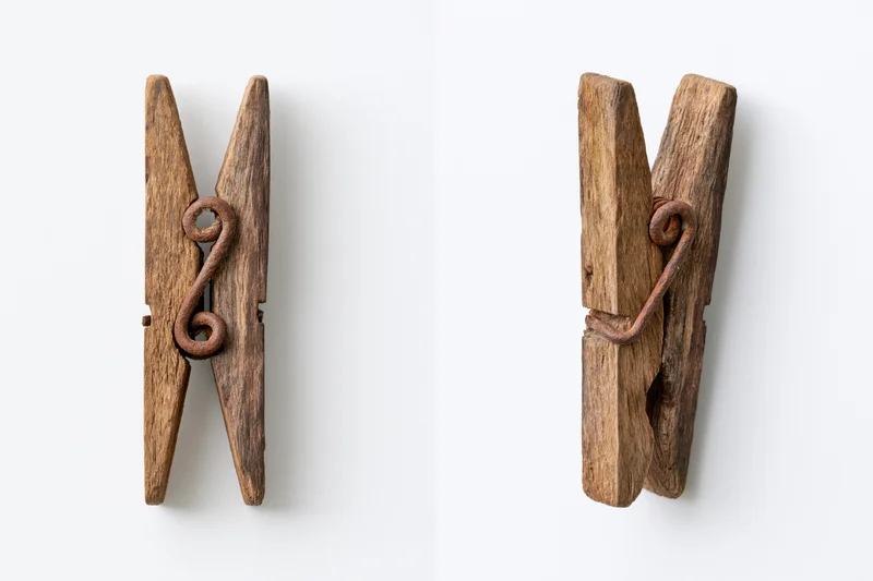 Two views of an aged wooden clothespin with metal spring on white background