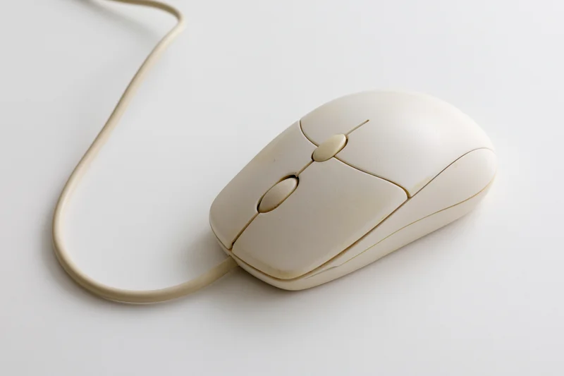 Vintage cream-colored wired computer mouse on white surface