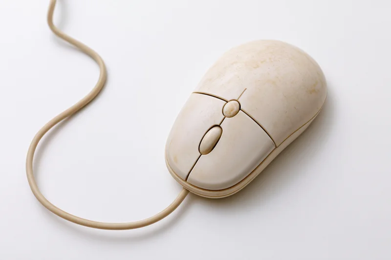 Vintage cream-colored wired computer mouse with three buttons on white surface