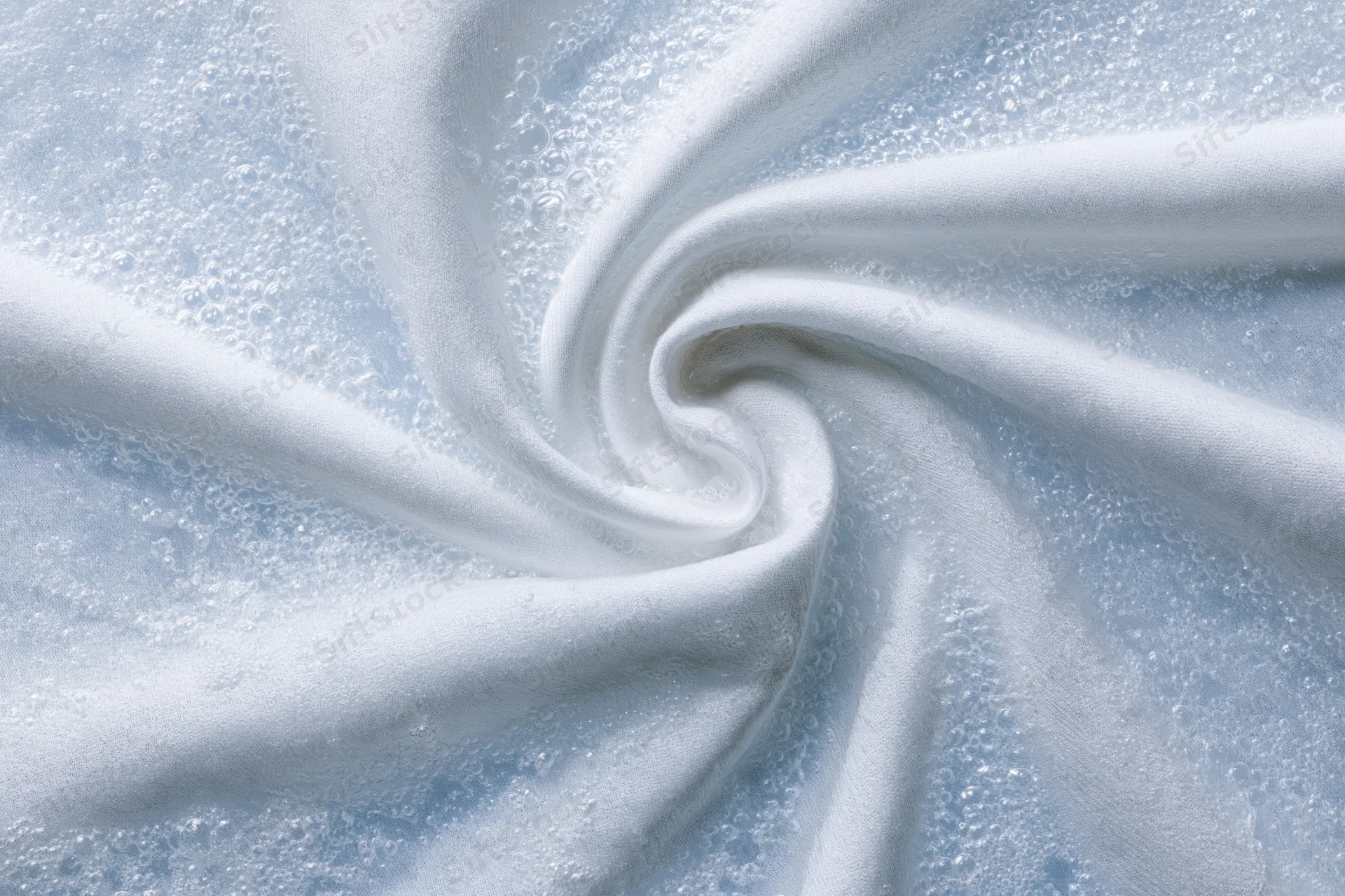 White fabric twisted into a spiral submerged in soapy water