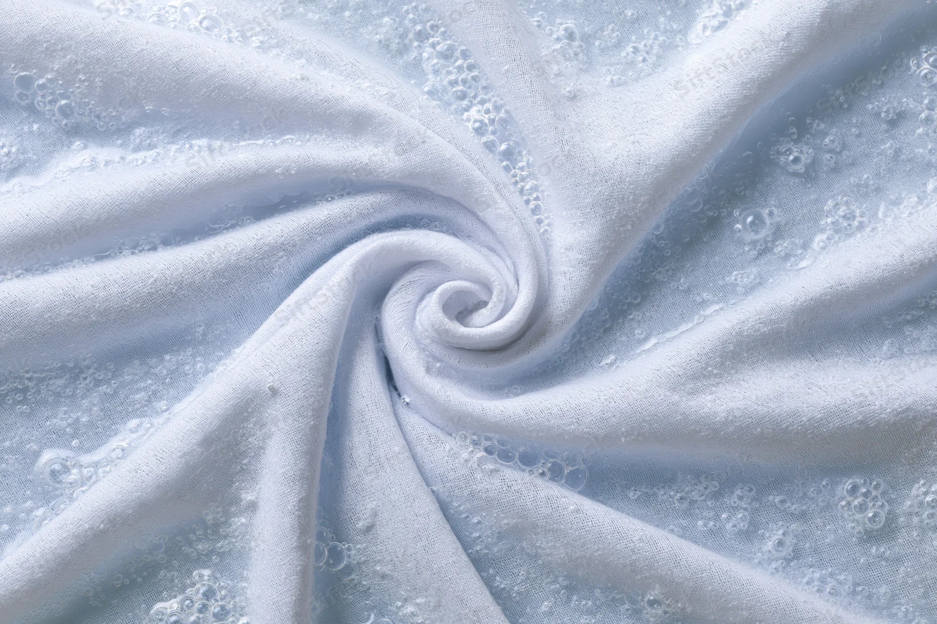 White fabric twisted into a spiral submerged in soapy water
