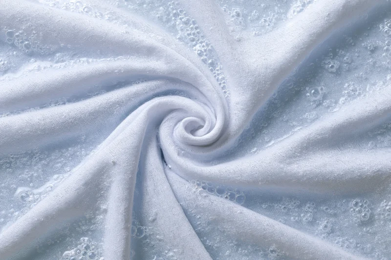 White fabric twisted into a spiral submerged in soapy water