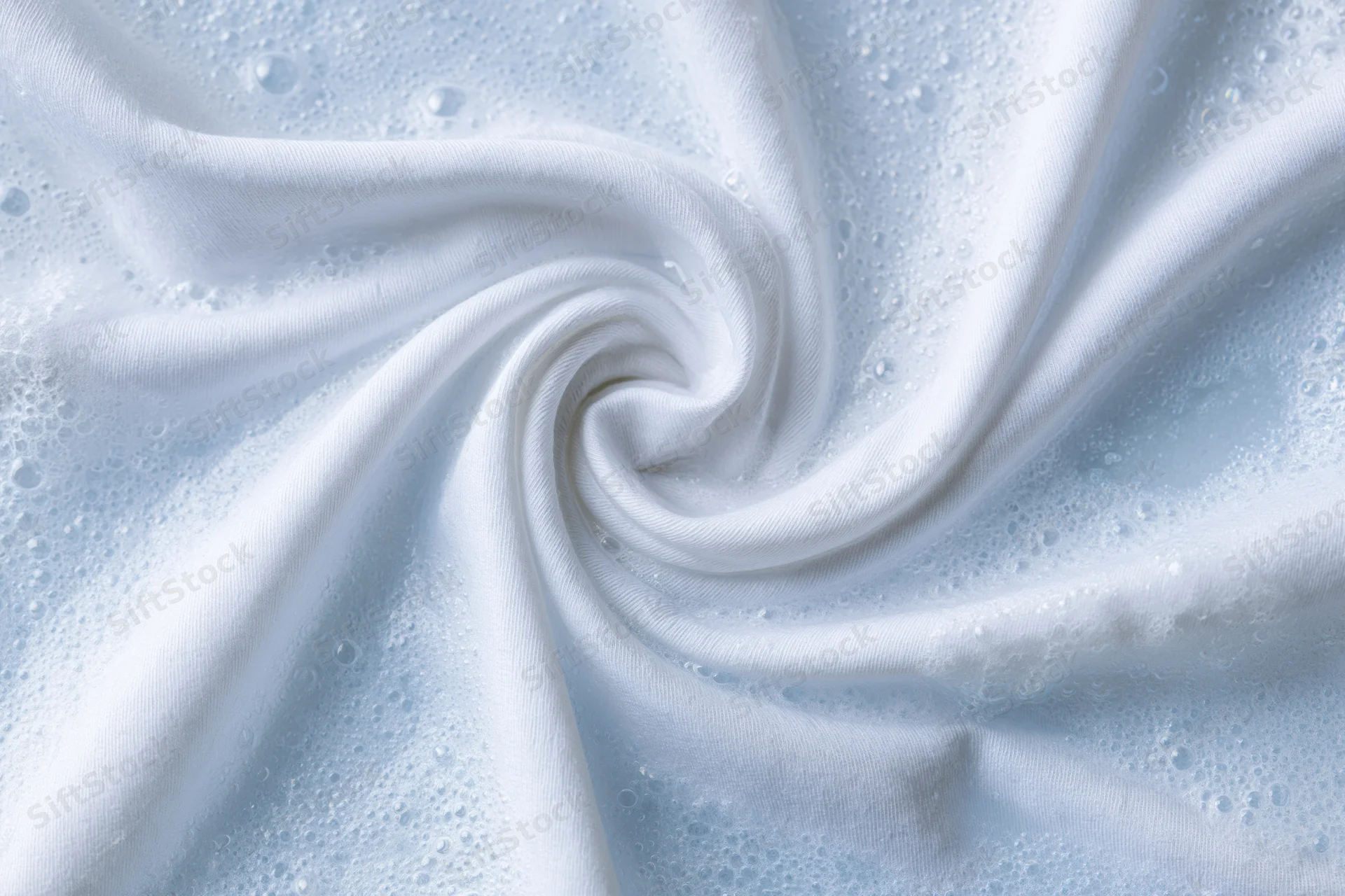 White fabric twisted into a spiral in soapy water