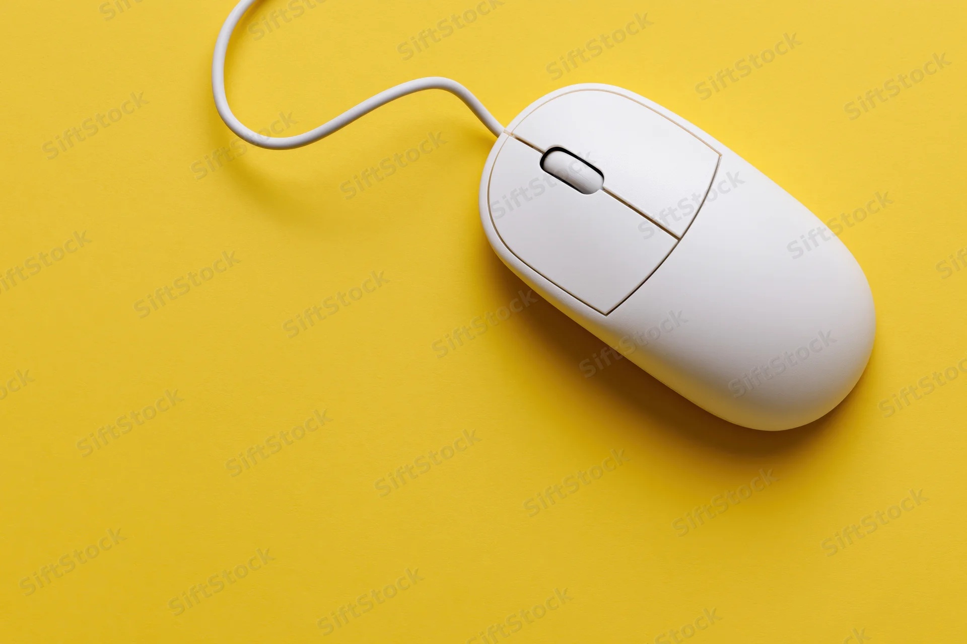 White wired computer mouse on yellow background with curved cable and copyspace