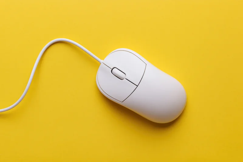 White wired computer mouse with curved cable on yellow background