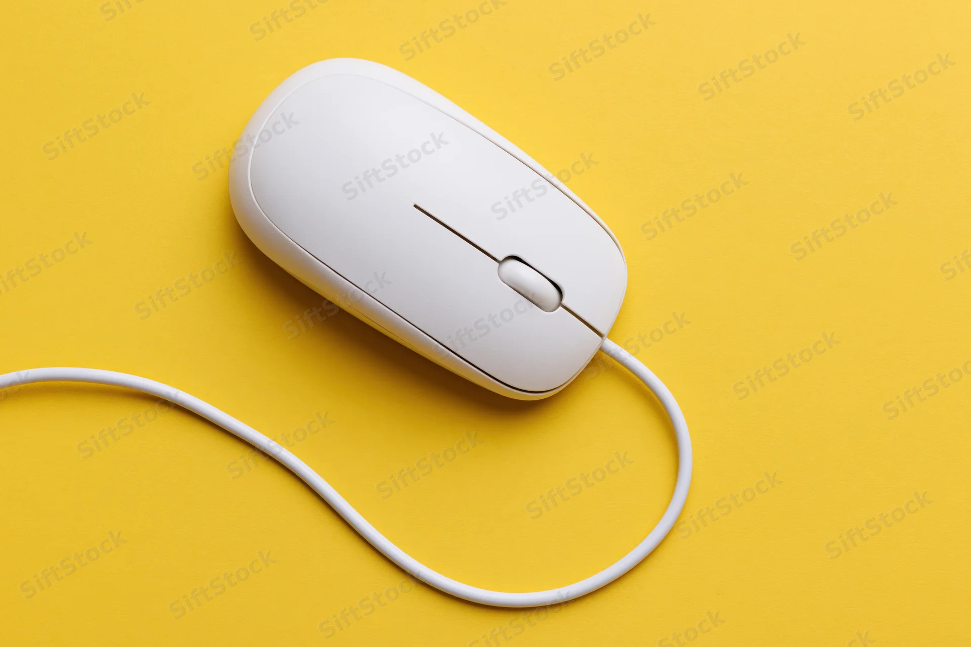 White wired computer mouse with curved cable on yellow surface