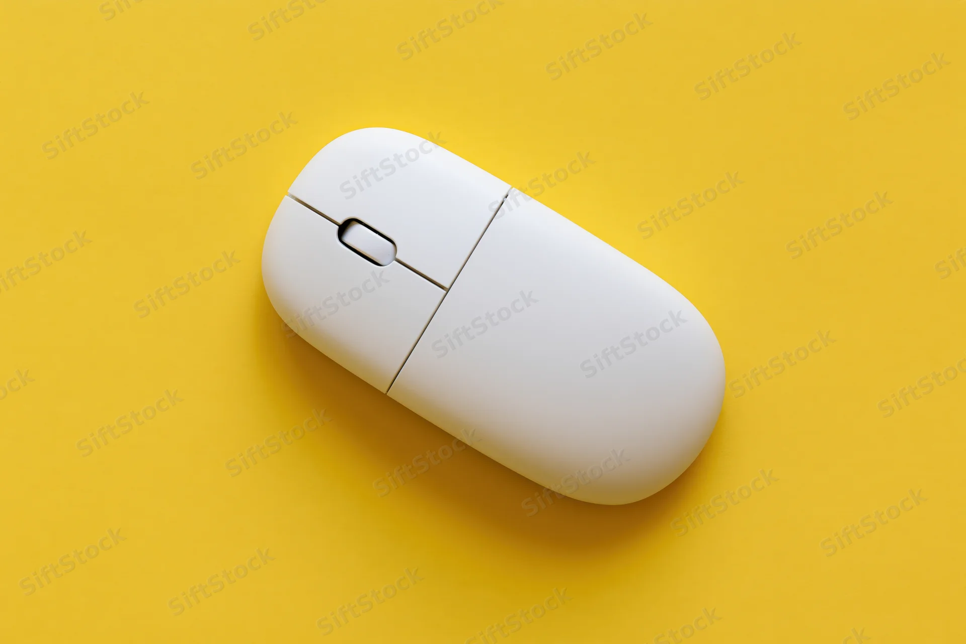 White wireless computer mouse centered on a flat yellow surface