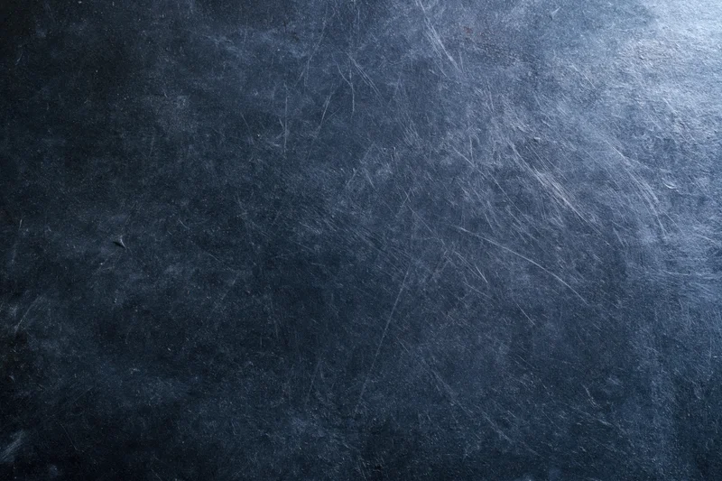 Dark scratched metal surface with worn texture and industrial finish