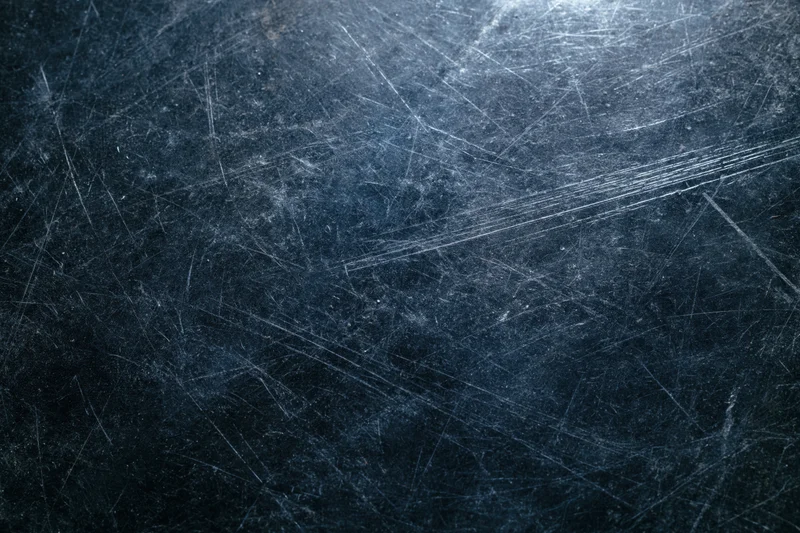 Dark scratched metal surface with fine scratches and reflective highlights