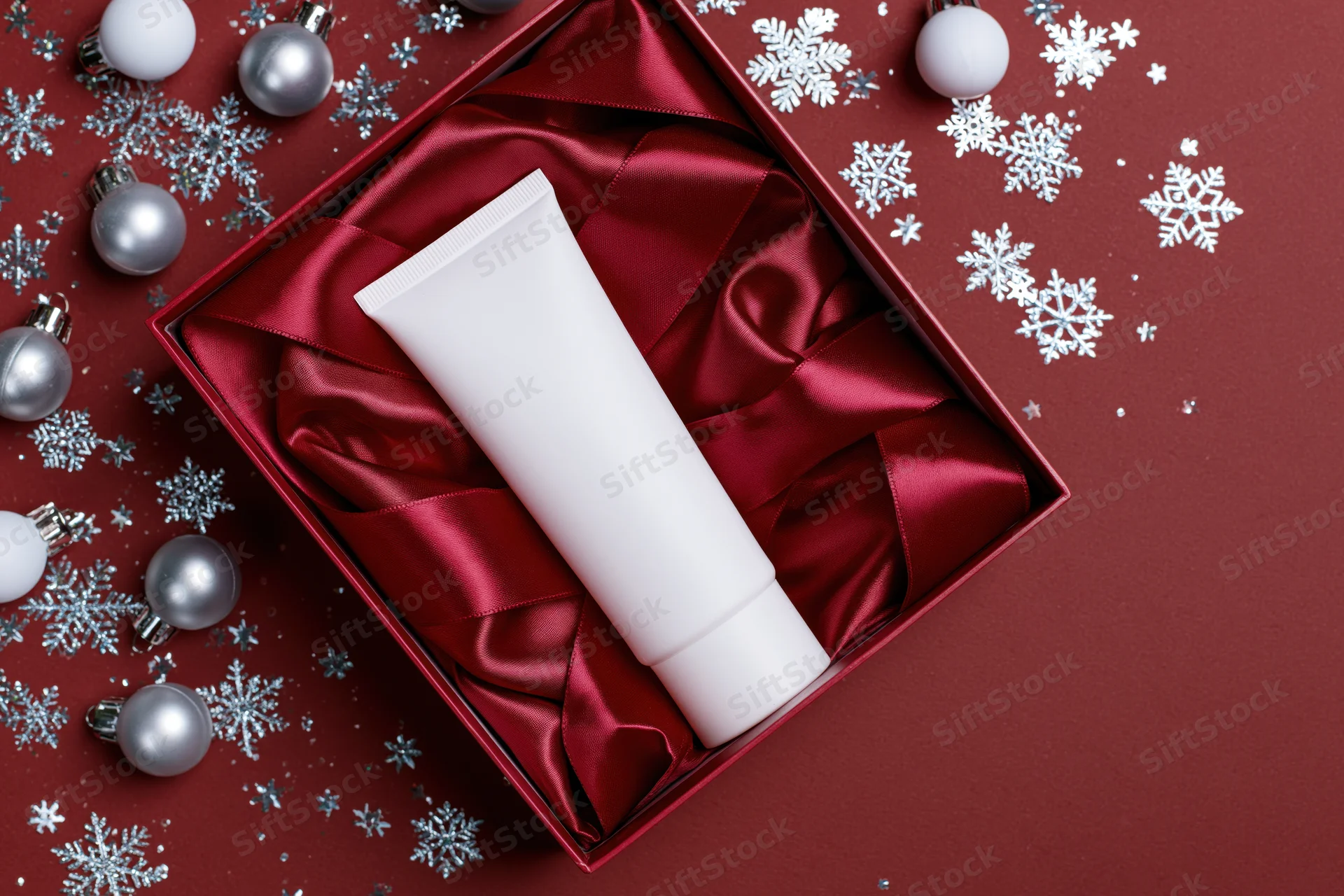 Blank white skincare tube in red gift box with festive decorations on red background