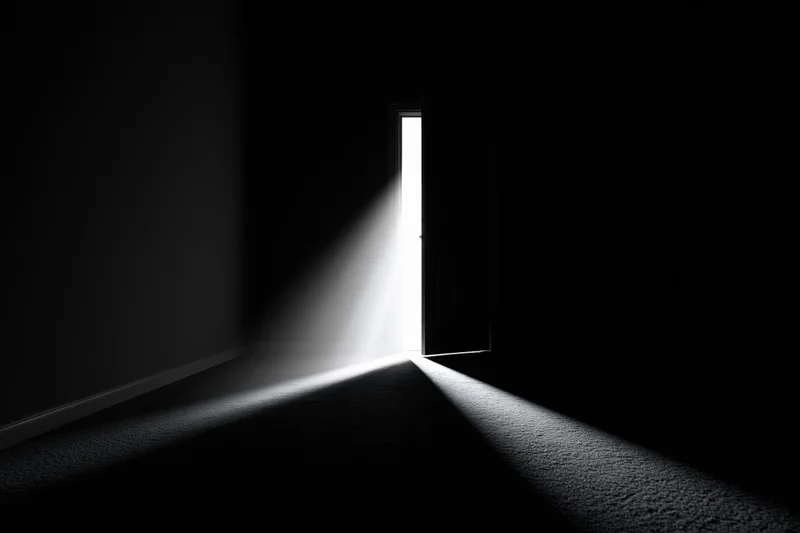 A slightly open door in a dark room casting a bright beam of light across the carpeted floor