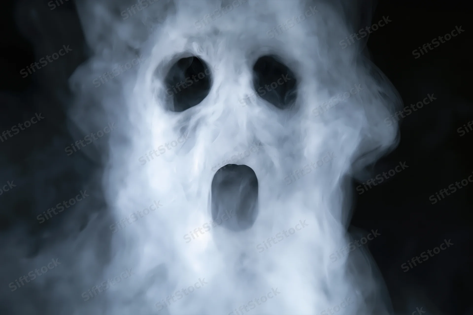 Ghostly screaming face emerging from dark smoke and fog