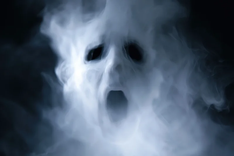 Ghostly screaming face emerging from dark smoke and fog