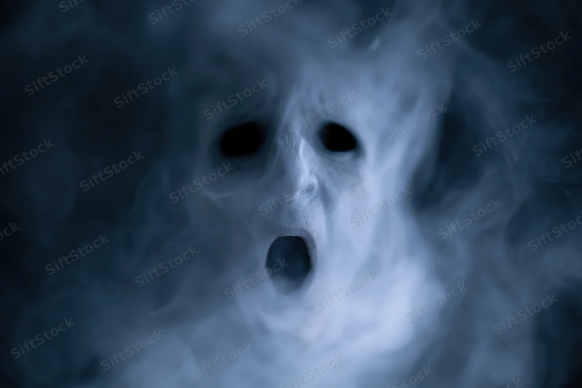 Ghostly screaming face emerging from dark smoke and fog