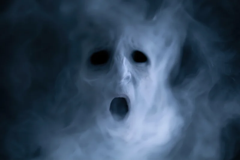 Ghostly screaming face emerging from dark smoke and fog