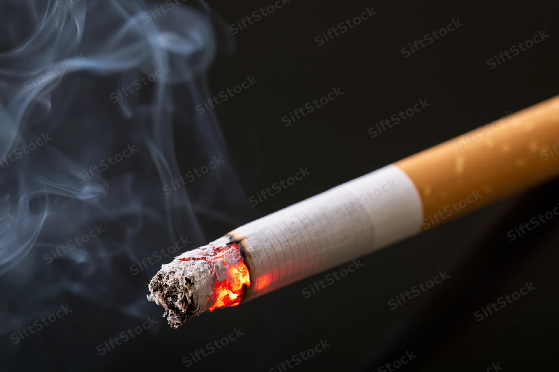 Lit cigarette with glowing ember and rising smoke against dark background