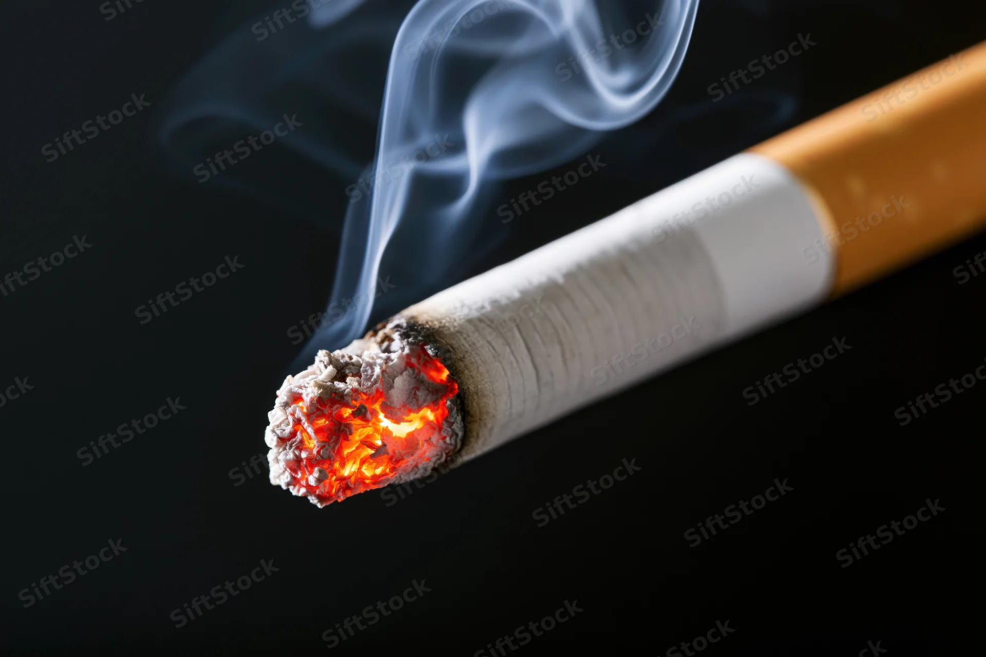 Lit cigarette with glowing ember and rising smoke against black background