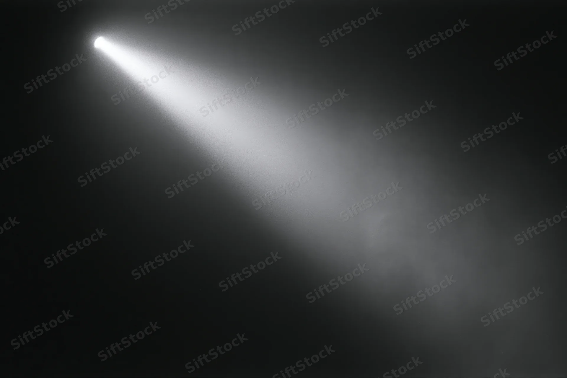A single beam of white light cutting diagonally across a dark smoky stage