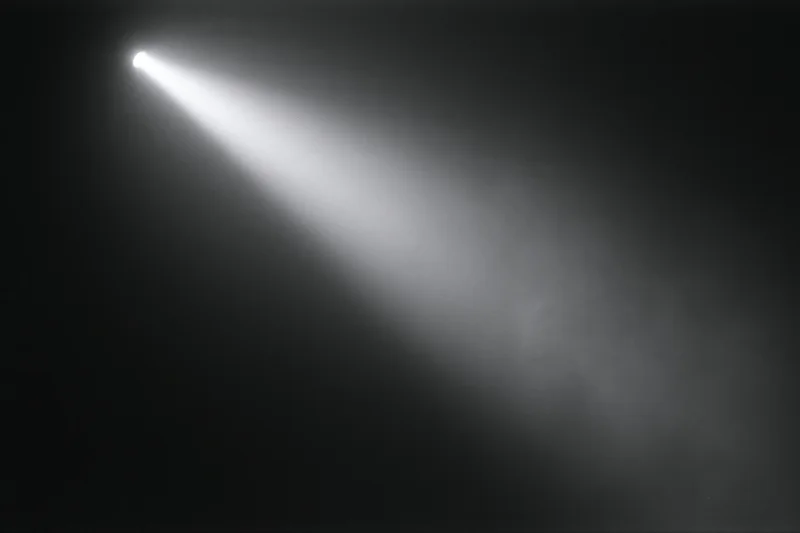 A single beam of white light cutting diagonally across a dark smoky stage