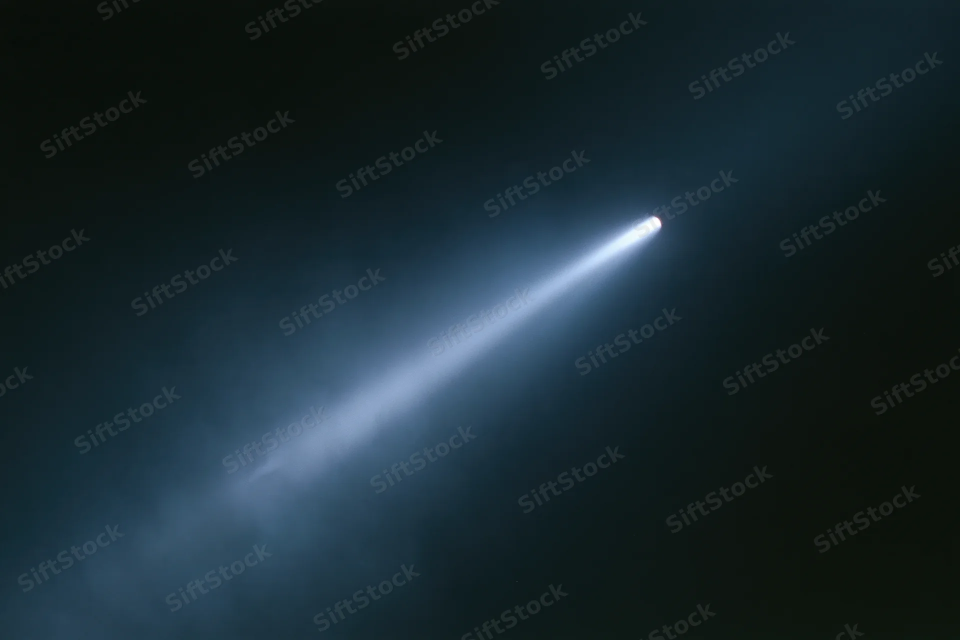 A single beam of cool white light cutting diagonally across a dark smoky space