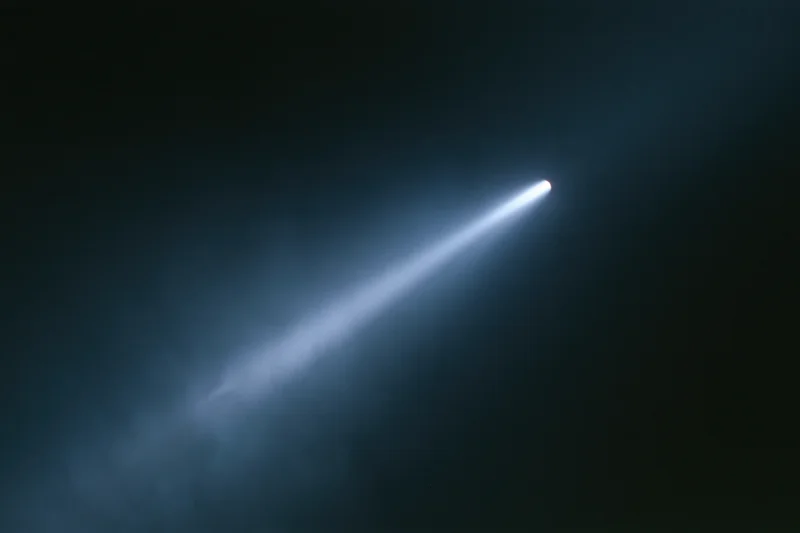A single beam of cool white light cutting diagonally across a dark smoky space