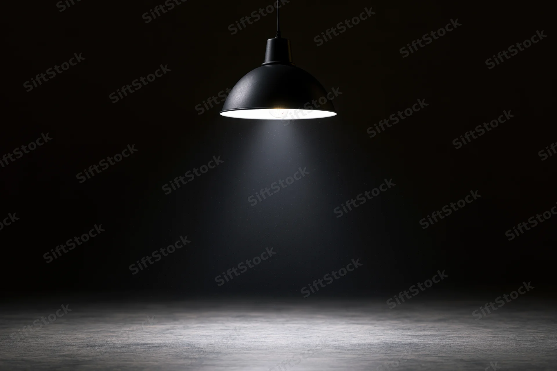 Black dome pendant lamp hanging from cord casting spotlight on concrete floor in dark space